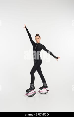 sportswoman en bottes pour le saut, femme en combinaison noire et chaussures de saut kangoo Banque D'Images