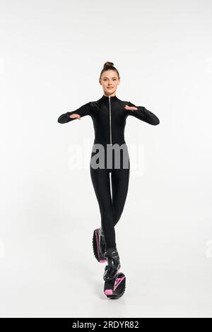 kangoo jumping concept, joyeuse sportswoman dans des bottes pour le saut et combinaison noire s'entraînant Banque D'Images