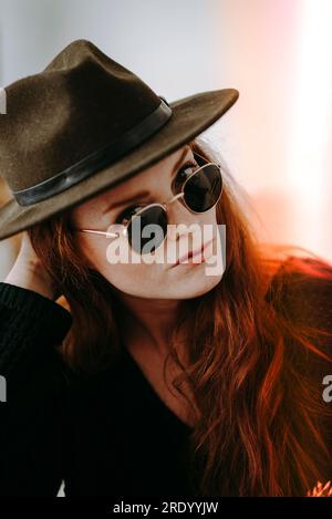 Gros plan de Redheaded Woman en lunettes de soleil et chapeau Banque D'Images