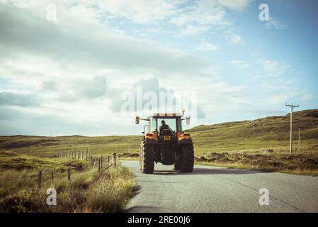 Le tracteur roule le long d'une route de campagne dans la région reculée de l'écosse Banque D'Images