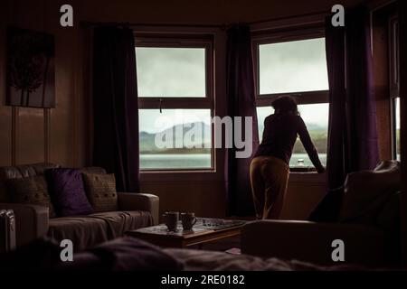 Silhouette de fille regardant par la fenêtre à vue sur la montagne Banque D'Images