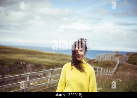 Les cheveux sauvages souffle dans le visage des filles sur la côte éloignée Banque D'Images