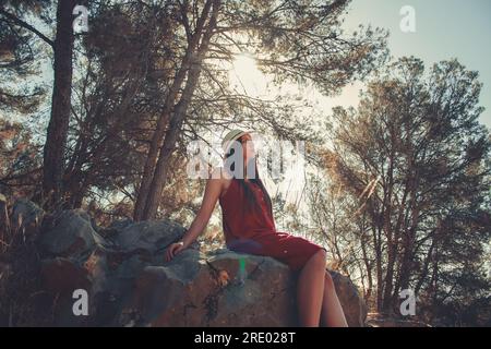 Femme dans une forêt assise sur des rochers dans une journée ensoleillée de printemps Banque D'Images