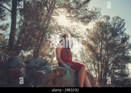 Femme dans une forêt assise sur des rochers dans une journée ensoleillée de printemps Banque D'Images