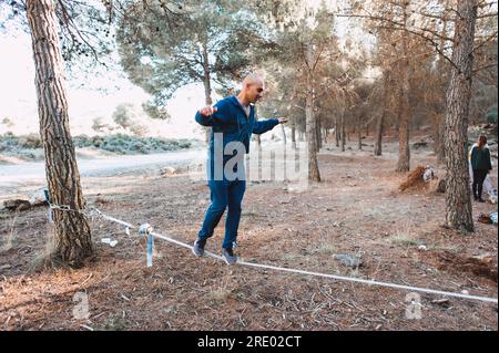 Jeune homme marchant sur slackline dans la forêt de pins à Grenade, Espagne Banque D'Images