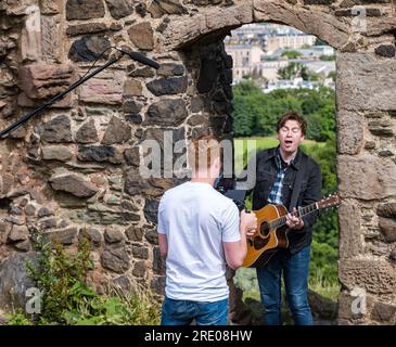 St Anthony's Chapel Holyrood Park, Édimbourg, Écosse, Royaume-Uni, 24 juillet 2023. Clip de Mike Baillie pour Fringe show : le chanteur du groupe The Lonely Together filme un nouveau clip pour son premier show Fringe Endless Sunset Oblivion qui raconte l'histoire d'un jeune compositeur Reuben qui tente de combattre les problèmes accélérés auxquels le monde est confronté. La chanson dans la vidéo a été écrite à cet endroit. Crédit : Sally Anderson/Alamy Live News Banque D'Images