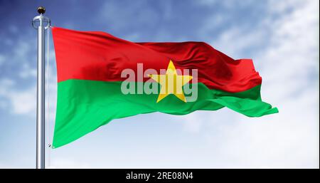 Drapeau national du Burkina Faso agitant dans le vent par temps clair. Deux bandes horizontales égales rouges et vertes avec une étoile jaune à cinq branches au centre Banque D'Images