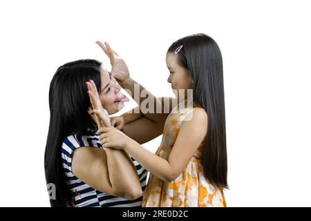 Jeune femme brune joue du singe pour amuser sa petite fille. Montrant la langue et les oreilles de la main. Isolé sur blanc. Banque D'Images