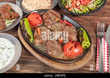 Cuisine turque Meat Shish. Shish kebab préparé sur un grill barbecue sur des charbons chauds avec des légumes grillés. Brochettes de viande cuites dans du beurre et du ragoût. Banque D'Images