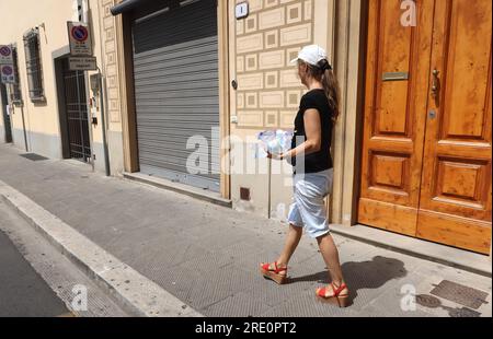 Florence, Italie. 19 juillet 2023. Femme apporte des bouteilles d'eau douce à Prato, dans la banlieue de Florence, région Toscane, Italie, le 19 2023 juillet. Des températures élevées devraient persister dans la plupart des régions du centre et du sud de l'Italie jusqu'en juillet 24 au moins. Des avertissements rouges de haute température ont été émis pour 23 villes, dont Bologne, Florence, Rome et Naples. (Photo Elisa Gestri/Sipa USA) crédit : SIPA USA/Alamy Live News Banque D'Images