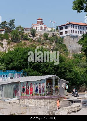 Plovdiv, Bulgarie. Entrée du métro et boutique avec illustrations de vêtements traditionnels. Église en arrière-plan sur la colline. Banque D'Images