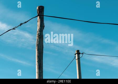 Deux poteaux électriques, un en bois et un en béton avec fils électriques, foyer sélectif Banque D'Images