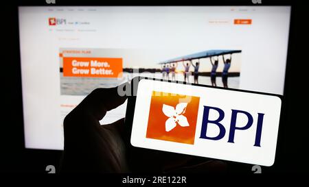 Personne détenant un téléphone portable avec le logo de Banco Portugues de Investimento S.A. (BPI) à l'écran devant la page Web. Concentrez-vous sur l'affichage du téléphone. Banque D'Images