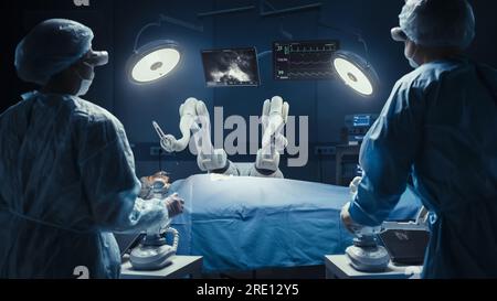 Deux chirurgiens observant des bras robotiques automatisés programmables de haute précision opérant un patient dans un hôpital de haute technologie. Membres robotisés pratiquant la chirurgie Banque D'Images