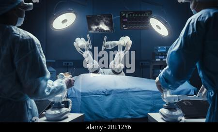 Deux chirurgiens observant des bras robotiques automatisés programmables de haute précision opérant un patient dans un hôpital de haute technologie. Membres robotisés pratiquant la chirurgie Banque D'Images