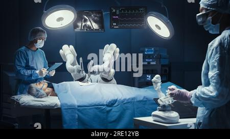 Deux chirurgiens observant des bras robotiques automatisés programmables de haute précision opérant un patient dans un hôpital de haute technologie. Membres robotisés pratiquant la chirurgie Banque D'Images