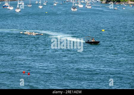 Petit bateau côtier remorquant des filets de crabe le long de l'estuaire de Salcombe dans l'eau calme avec des yachts mordus en arrière-plan un jour d'été. Banque D'Images