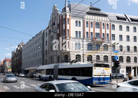 Bâtiments, magasins et circulation dense avec des voitures et trolleybus articulés à l'intersection de la rue Brīvības à Riga Banque D'Images