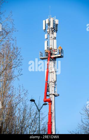 Déploiement de la 5G en France : installation de stations relais de téléphonie mobile avec plateforme aérienne de travail. Techniciens au travail. Téléphone français et Internet pro Banque D'Images