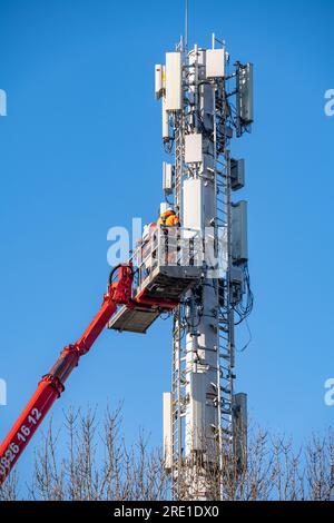 Déploiement de la 5G en France : installation de stations relais de téléphonie mobile avec plateforme aérienne de travail. Techniciens au travail. Téléphone français et Internet pro Banque D'Images