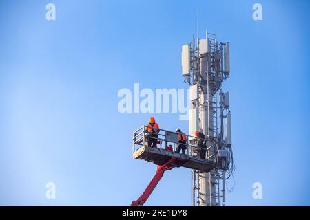 Déploiement de la 5G en France : installation de stations relais de téléphonie mobile avec plateforme aérienne de travail. Techniciens au travail. Téléphone français et Internet pro Banque D'Images