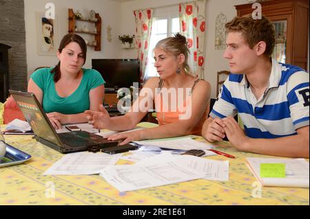 Visite d’un comptable agréé à la ferme d’un jeune couple. Expert-comptable agréé et jeune couple d'agriculteurs lisant des documents : plan de compte Banque D'Images