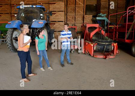 Visite d’un comptable agréé à la ferme d’un jeune couple. Comptable agréé et quelques jeunes agriculteurs visitant la ferme, regardant l'équipement Banque D'Images
