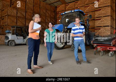 Visite d’un comptable agréé à la ferme d’un jeune couple. Comptable agréé et quelques jeunes agriculteurs visitant la ferme, regardant l'équipement Banque D'Images
