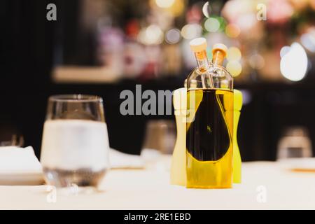 Une bouteille en verre avec de l'huile d'olive et du vinaigre balsamique sur la table. Banque D'Images