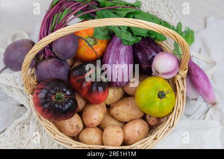 Panier avec divers légumes. Pommes de terre, betteraves, tomates, échalotes, aubergines. Style campagnard. Vue de dessus. Banque D'Images