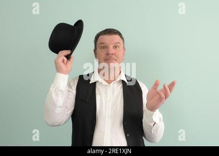 Un homme du passé, un portrait sur fond clair. Chapeau Bowler, geste de bienvenue Banque D'Images