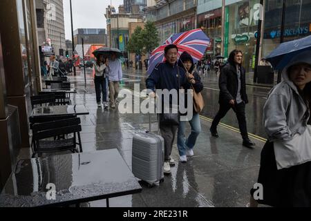 Les touristes sur Oxford Street dans l'abri West End de Londres forment les fortes averses de pluie estivales sous les parapluies pendant qu'ils font du shopping, Angleterre, Royaume-Uni Banque D'Images