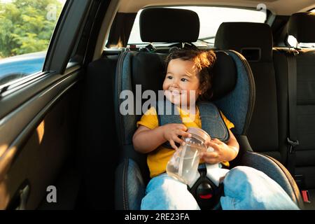 Adorable bébé asiatique appréciant voyage en voiture assis dans le véhicule Banque D'Images