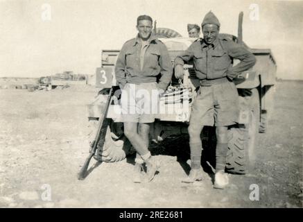 Libye. 1942. Soldats britanniques posant pour une photographie alors qu ' ils s ' appuyaient contre un camion de 3 tonnes Chevrolet C60 Canadian Military Pattern (CMP) dans le désert occidental en avril 1942, pendant la campagne d ' Afrique du Nord de la Seconde Guerre mondiale. L’un des fusils Lee Enfield du soldat est également appuyé contre le camion. Banque D'Images