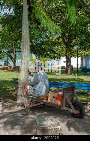 Pêcheur dévoué réparant le filet de pêche sur la place, un aperçu de la vie côtière authentique à Rio de Janeiro, Brésil Banque D'Images