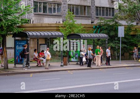 Kazakhstan, Almaty. Scène de rue : passagers attendant le bus à l'arrêt de bus. Banque D'Images