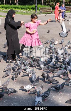 Kazakhstan, Almaty. Jeunes filles Feediung Pigeons devant la cathédrale de l'Ascension, orthodoxe russe. Banque D'Images