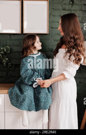 Fête des mères. Une jeune maman sensible embrasse sa petite fille adorable à la maison. Confiance, soutien et amour entre maman et enfant. Une famille aimante Banque D'Images