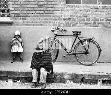 Chia, Colombie : c. 1960 Un homme assis sur le trottoir dans une rue de Chia, juste au nord de Bogota en Colombie. Banque D'Images