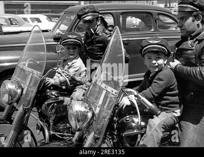 San Francisco, Californie vers 1954 deux motards portant des casquettes et des vestes en cuir sur leurs Harley Davidsons avec leurs petits fils devant eux. Les garçons portent des casquettes qui disent "Harley Davidson Motor cycle". Banque D'Images