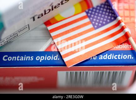 Un concept de toxicomanie avec le drapeau américain et des boîtes de médicaments contenant des opioïdes et avertissant de la dépendance. Banque D'Images