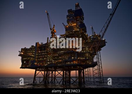 Plate-forme pétrolière et gazière offshore dans la mer au coucher du soleil. Banque D'Images