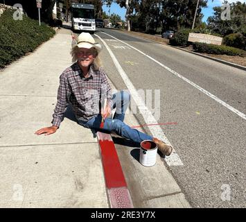 Montecito, Californie, États-Unis 24 juillet 2023. Clint Orr, un natif de Santa Barbara, qui vivait dans les rues de Montecito depuis plus de 10 ans '' maison de la riche élite américaine, y compris les stars de cinéma et la royauté ''' peint les bordures de rue fanées devant Starbucks, l'un des établissements qu'il fréquente sur Coast Village Road, le principal prix complet à travers la ville de plage autrement conte de fées. Montecito ressemble à Tijuana. Au lieu de blâmer quelqu'un pour cela, je fais juste ce que je peux pour apporter des améliorations!'' il a acheté sa propre peinture et son propre pinceau, et il a également peint Banque D'Images