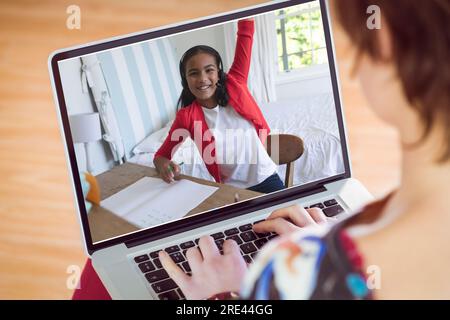 Fille caucasienne regardant un ami levant la main sur appel vidéo sur ordinateur portable pendant le cours en ligne Banque D'Images