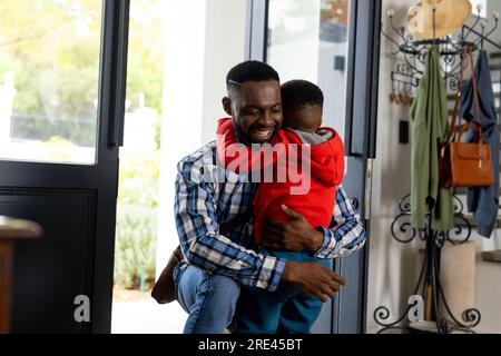 Heureux père afro-américain serrant son fils dans la porte d'entrée à la maison Banque D'Images