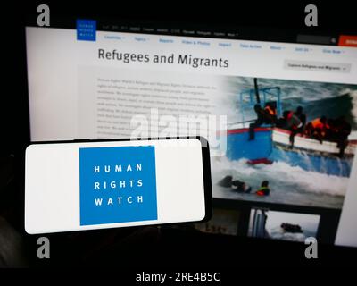 Personne tenant un téléphone portable avec le logo de l'organisation Human Rights Watch (HRW) sur l'écran devant la page Web. Concentrez-vous sur l'affichage du téléphone. Banque D'Images