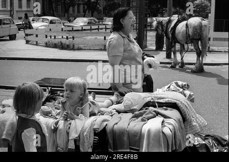 Portobello Road, marché du samedi, Notting Hill West London 1970s. Le bout haut et bon marché de la route. Vieux vêtements vendus par mère avec ses deux enfants. Cheval gitan en arrière-plan. Angleterre. ANNÉES 1975 70 ROYAUME-UNI HOMER SYKES Banque D'Images