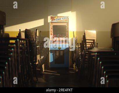 Une armoire de jeux vidéo d'arcade Nintendo Donkey Kong sur un mur jaune dans une pièce flanquée de chaises empilées éclairées par une lumière de fenêtre - 25 juillet 2023 Banque D'Images