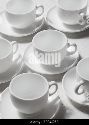 Fond d'un ensemble de plats en céramique blanche, tasses et soucoupes pour le thé ou le café Banque D'Images