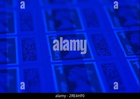 Angleterre, le 25 juillet 2023 : faux timbres Royal Mail 1st Class large Letter sous lumière UV. - Contrefaçons Royal Mail timbres à code-barres sont en vente sur eBay à une fraction du prix réel. Des feuilles de 50 timbres sont en vente aussi bas que 15 livres (GBP) et à l'oeil peu méfiant ont l'air réel. Cependant, sous la lumière UV, de petites différences peuvent être observées. Crédit : Arrêter Press Media/Alamy Live News Banque D'Images